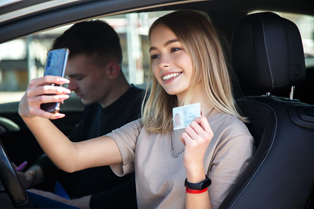 girl smiling and taking selfie with her new driver's license